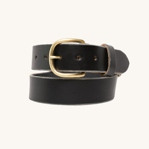 A black full grain leather belt with a rounded solid brass buckle, shown coiled against a light neutral background.