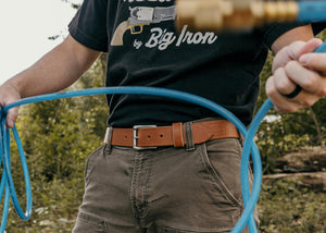 Person holding blue hose with blurred natural background